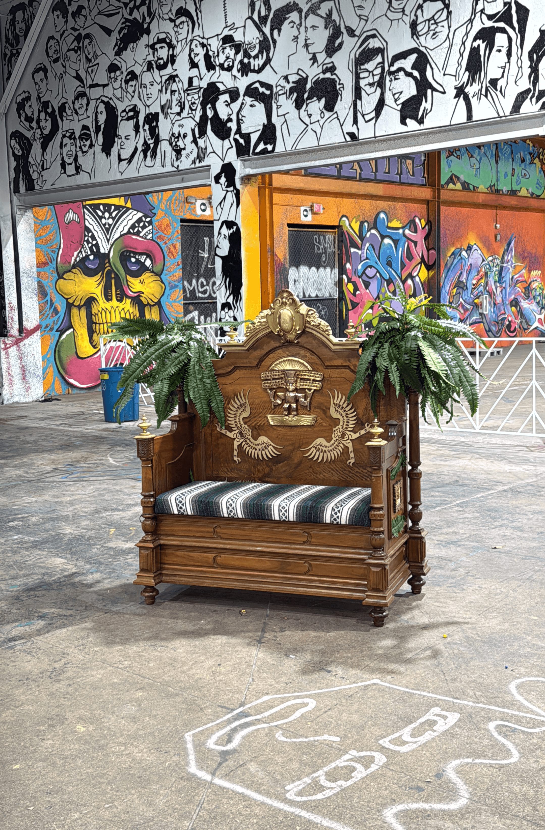 Decorative wooden bench with plants in an urban graffiti-covered space, with black and white wall art above.