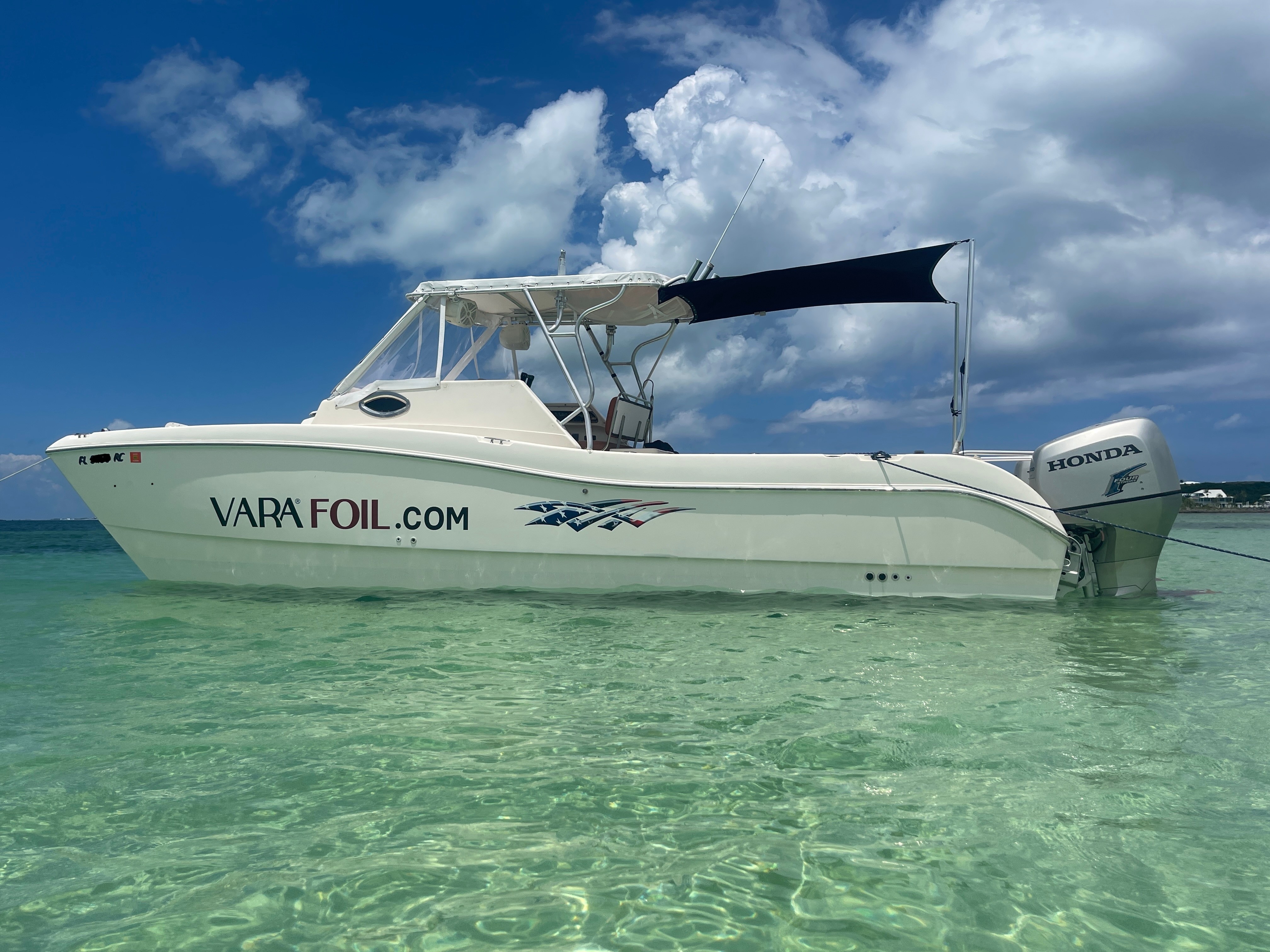Motorboat floating on clear water with cloudy sky background.