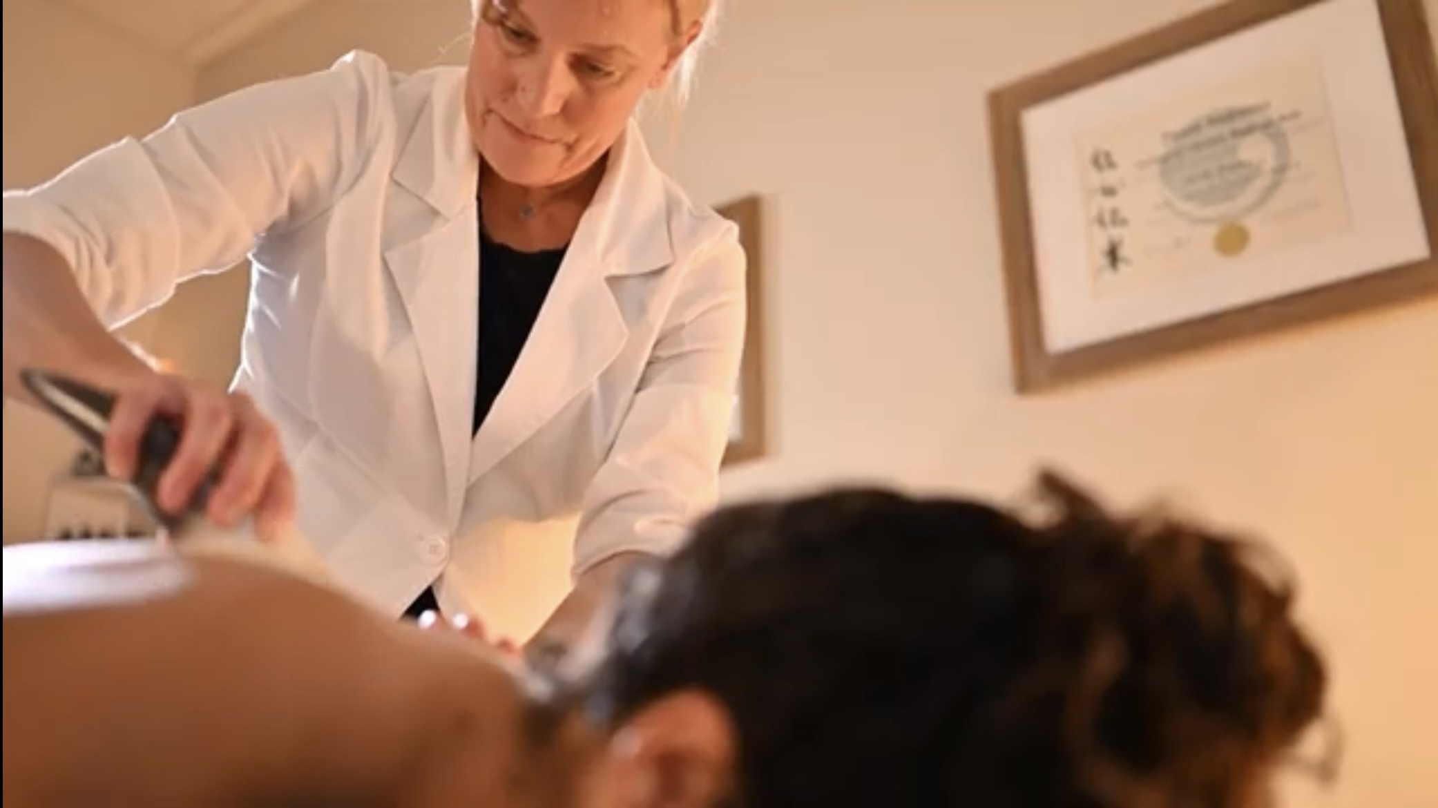 Medical professional in white coat examining a patient lying down.