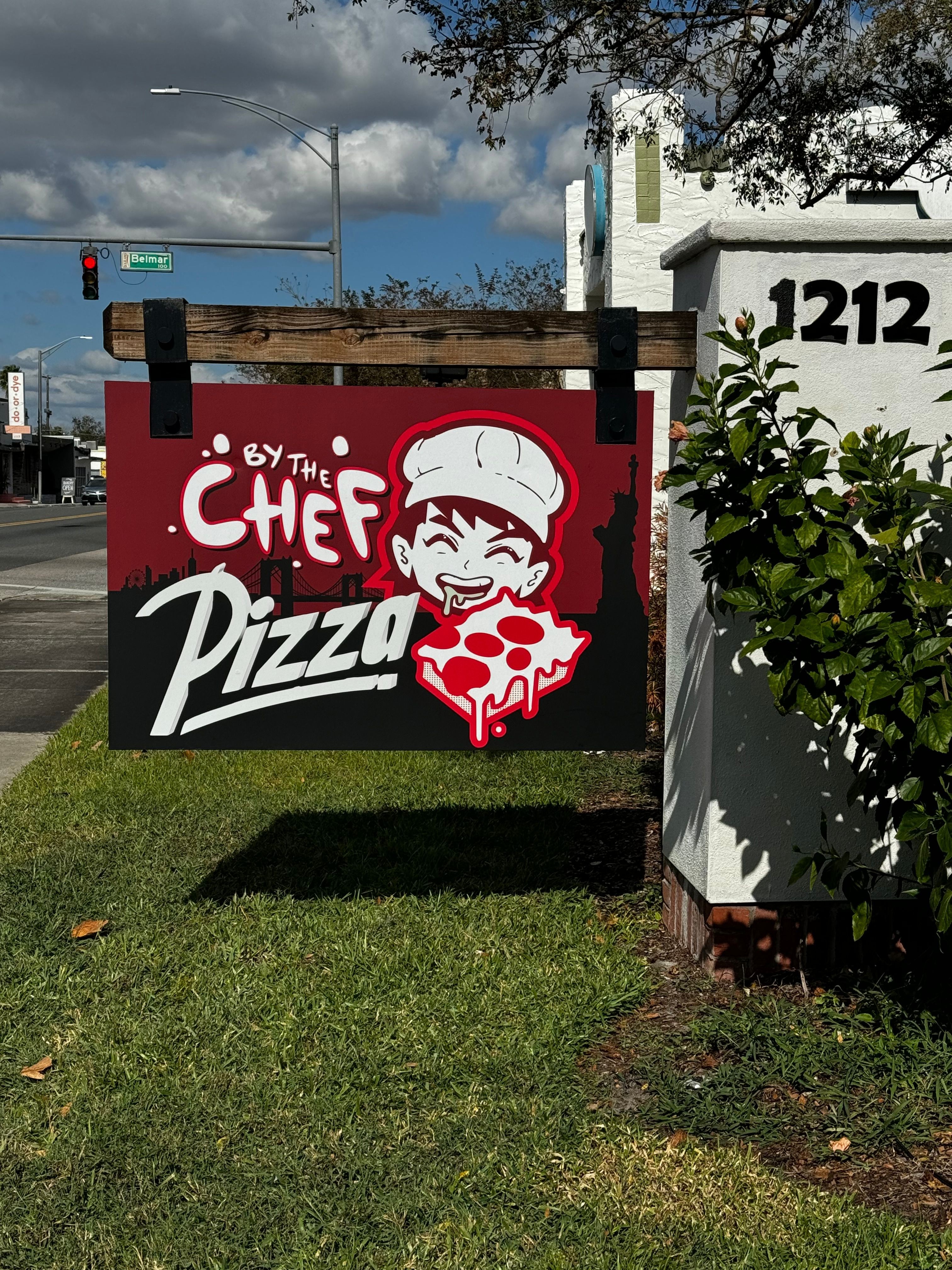 Pizza restaurant sign with a chef's face and a pizza slice, red background, and white text.