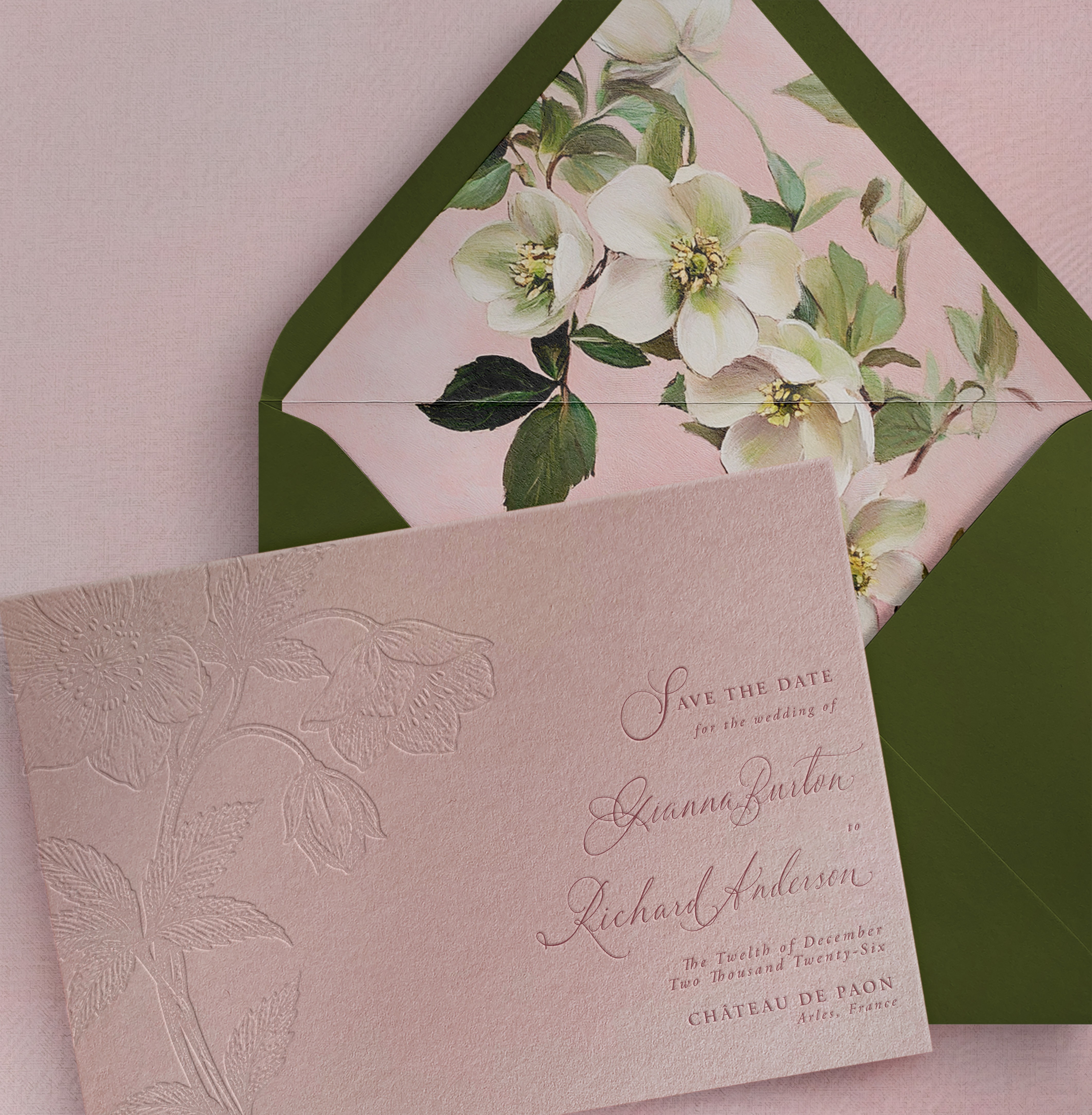 Invitation card with floral design, partially inside a green envelope, on a pink background.