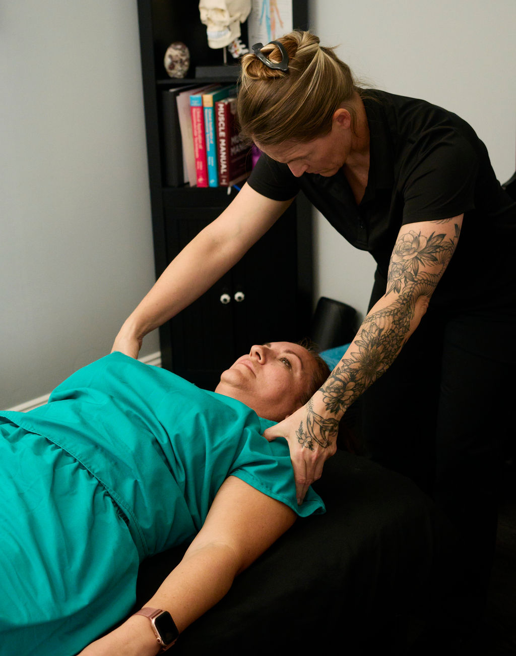 A healthcare worker adjusts a patient's head on a medical examination table in a clinical setting.