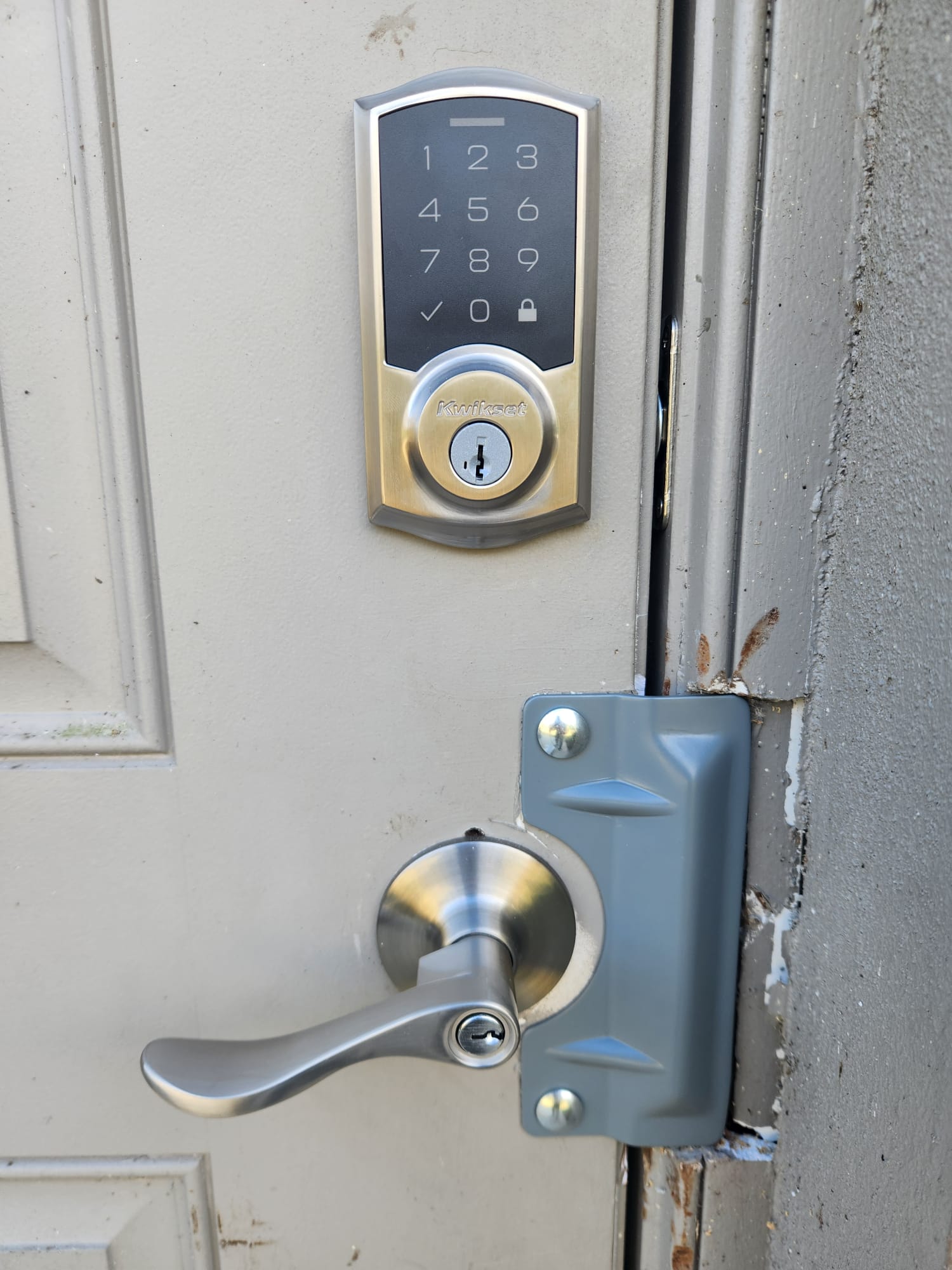 Door with keypad lock and handle, gray door frame, and visible wear on the door edge.