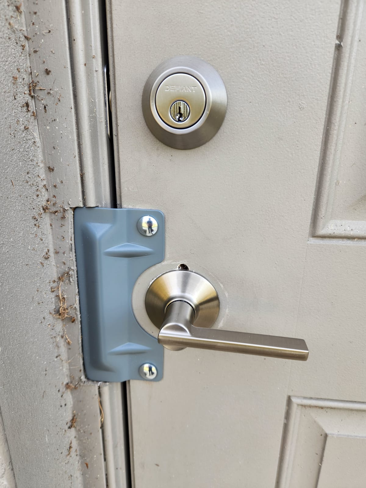 Close-up of a door with a silver handle, a blue lock box, and a round deadbolt lock above, on a white door.