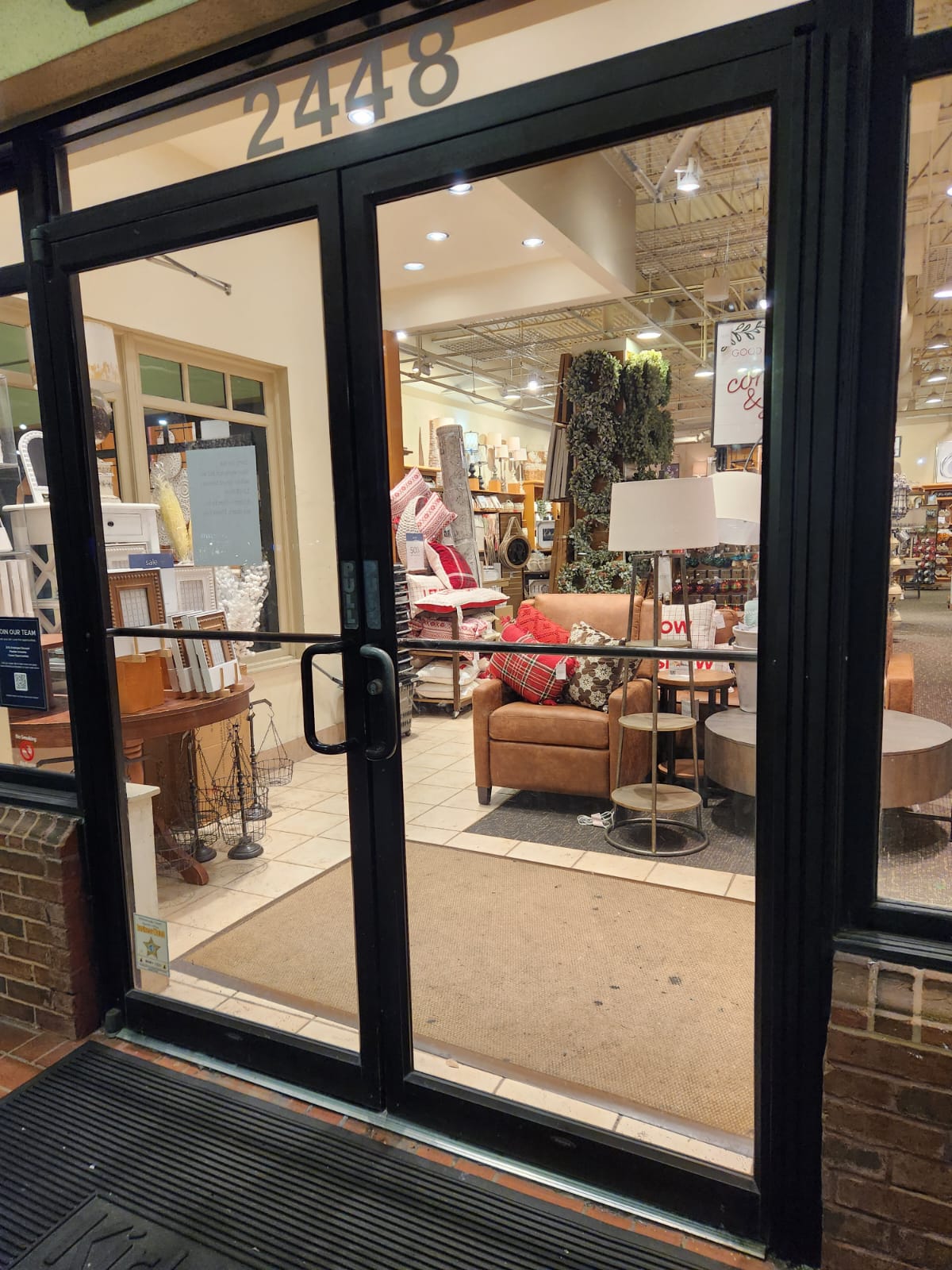 Store entrance with glass doors, furniture display inside, and the number 2448 above the door.