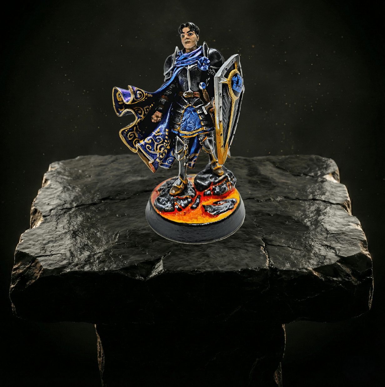 Miniature figure of a warrior in blue armor with a shield, standing on a fiery base, on a black stone surface.