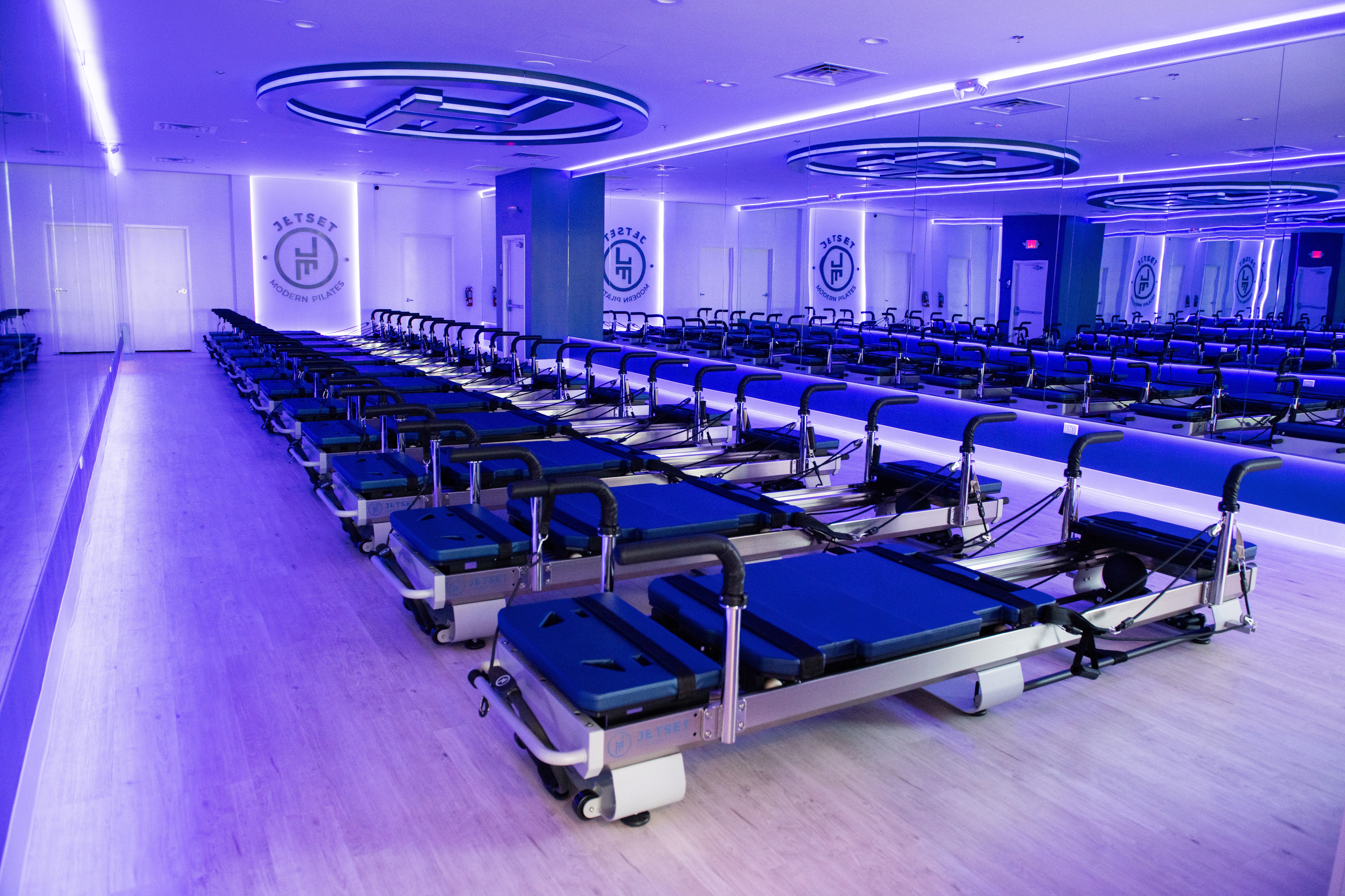 Hospital beds arranged in rows in a brightly lit room with blue lighting and circular ceiling features.