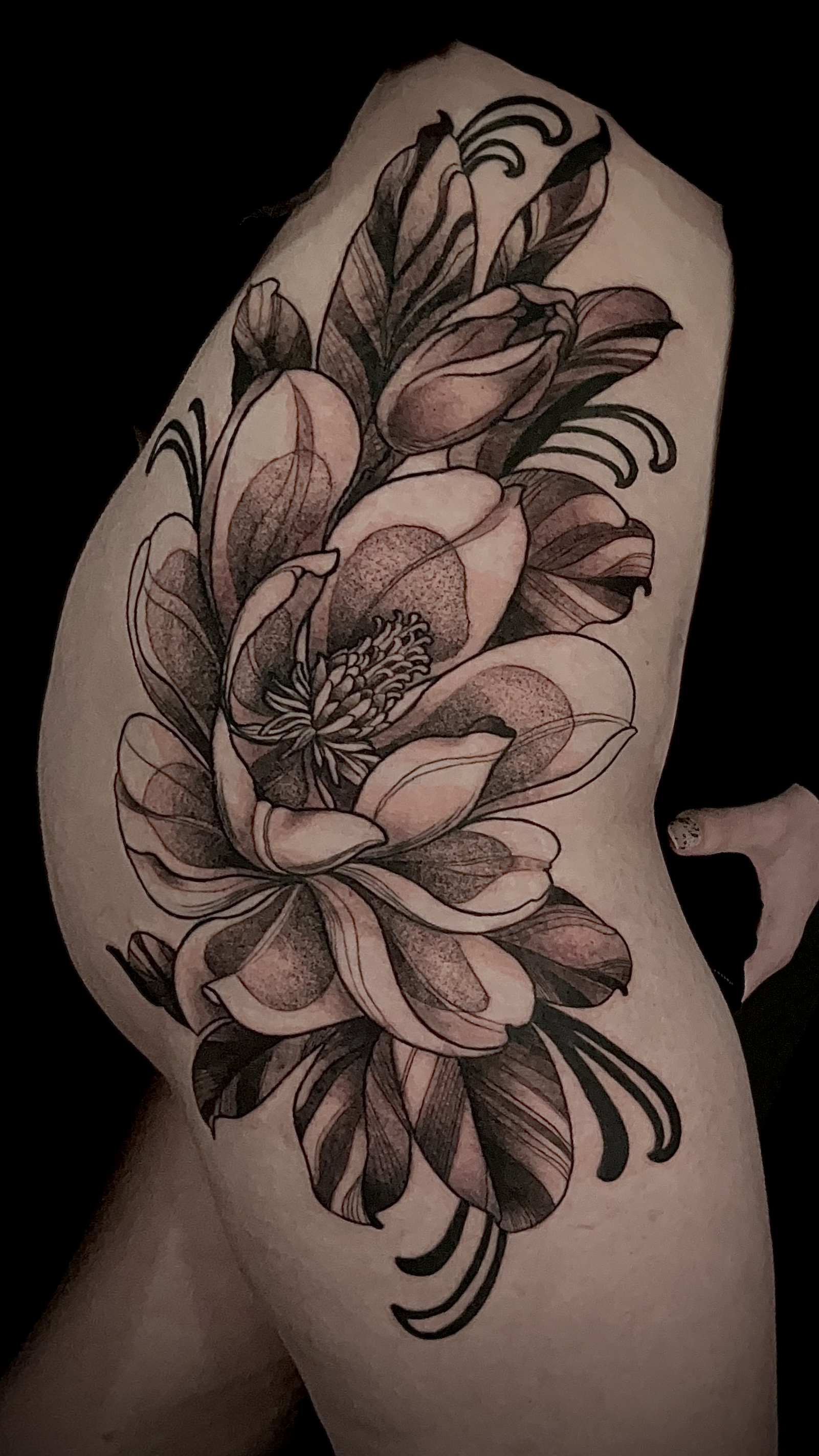 Side view of a person's torso with a large, detailed floral tattoo featuring blooming flowers and leaves.