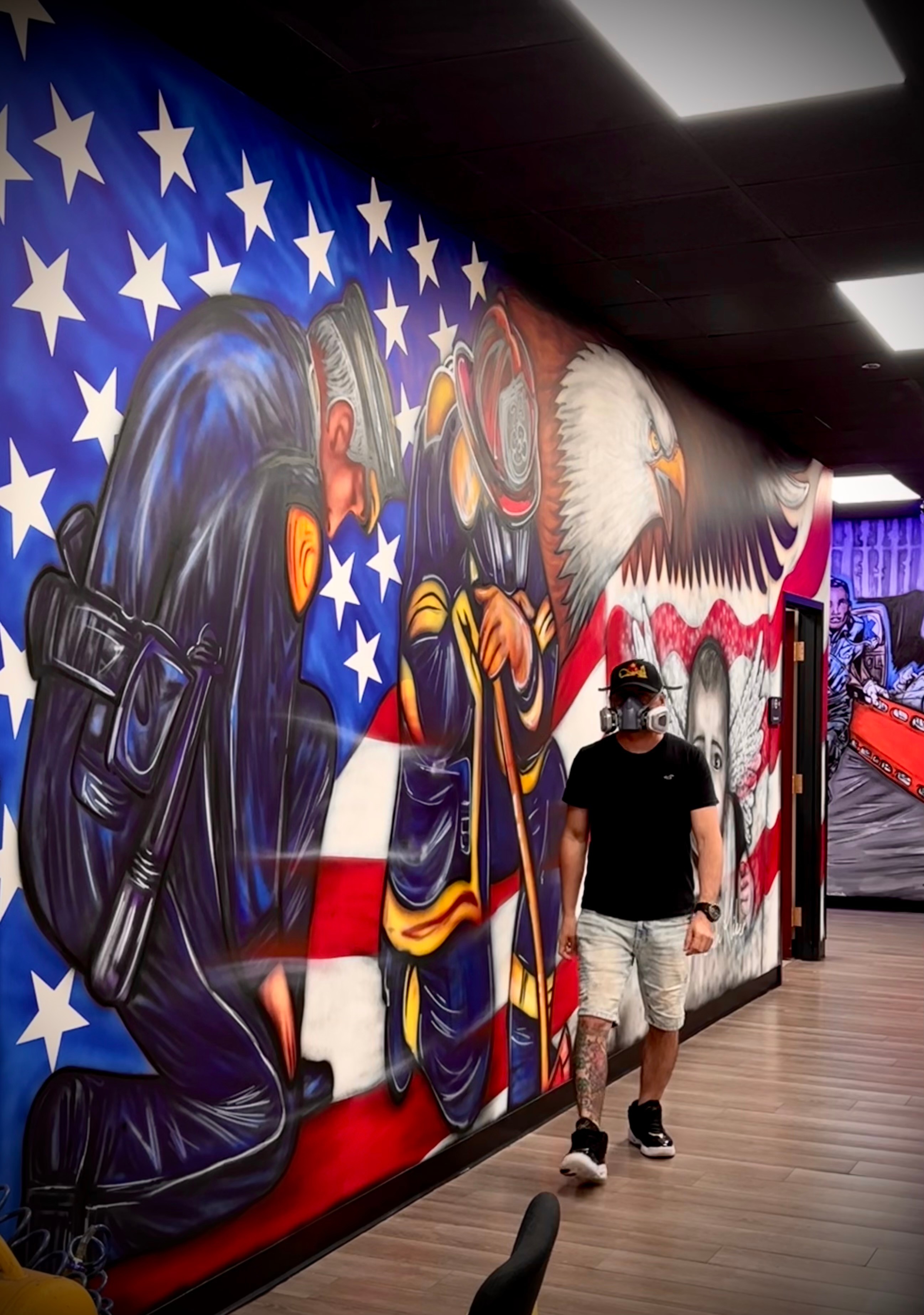 Person walking past a mural of a police officer and an eagle with an American flag background, in an indoor setting.