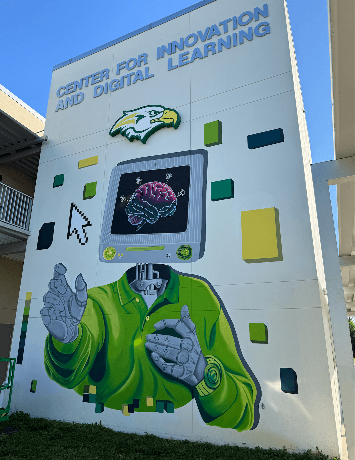 Wall mural with a robot with a computer head displaying a brain, wearing a green jacket, pointing with one hand, and a cursor icon. Text at top reads 'Center for Innovation and Digital Learning'.