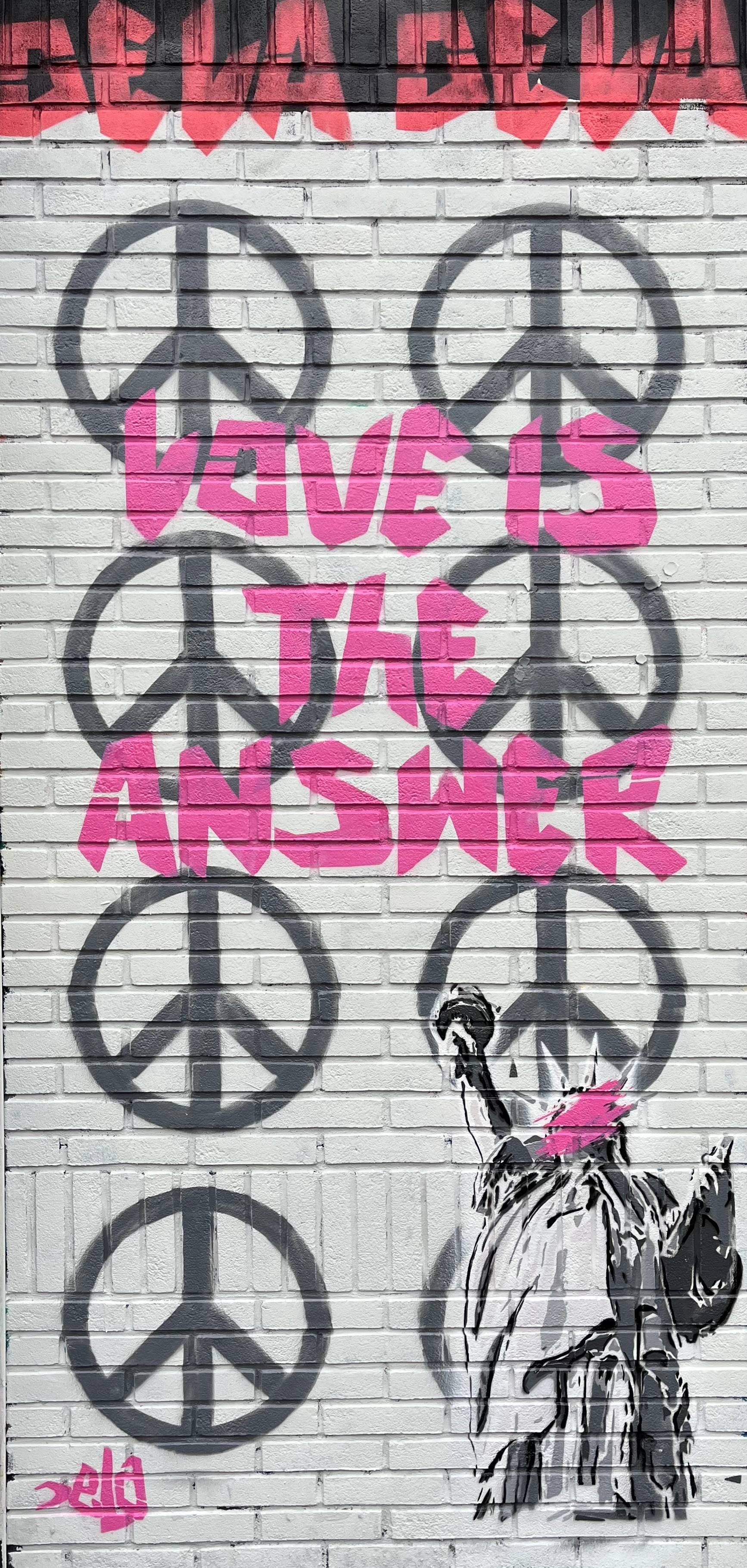 Graffiti with peace symbols, pink text reading 'LOVE IS THE ANSWER,' and a black and white image of a person with a dog.