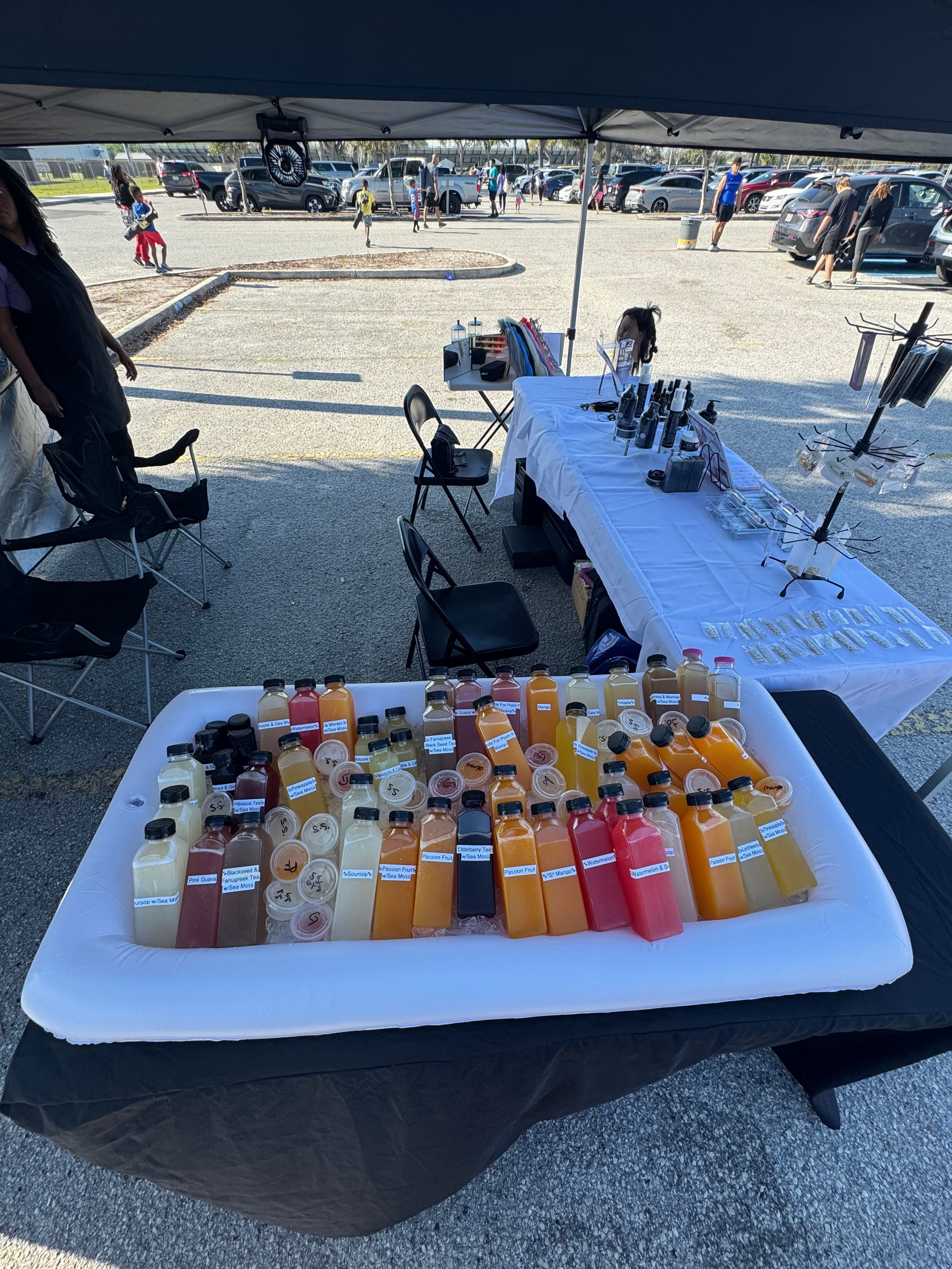 Table with bottles of beverages outdoors, with chairs and a street scene in the background.