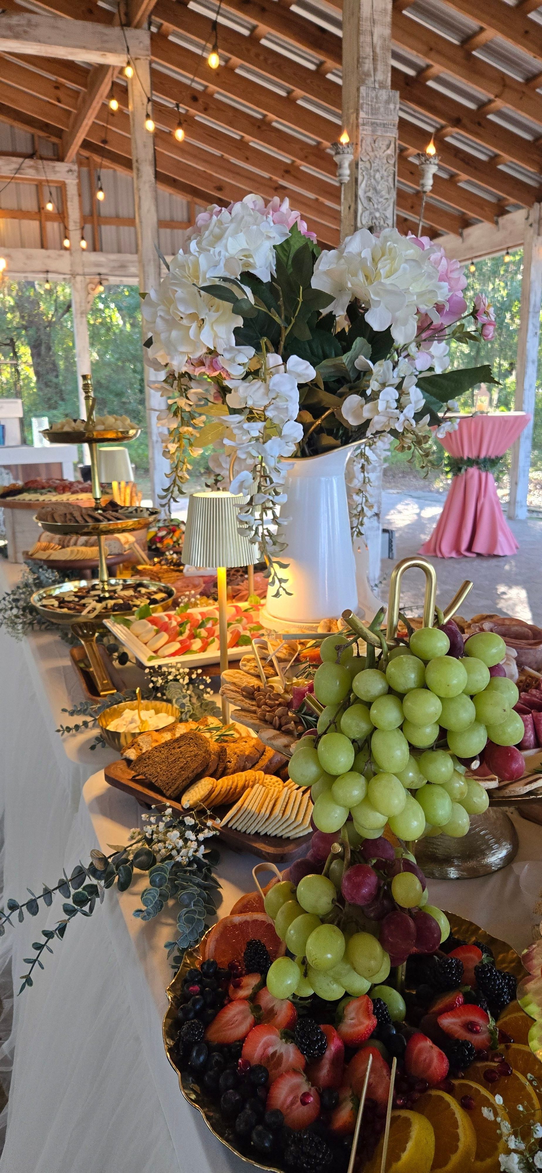 Decorative table with grapes, flowers, and candles in a bright, wooden indoor setting.