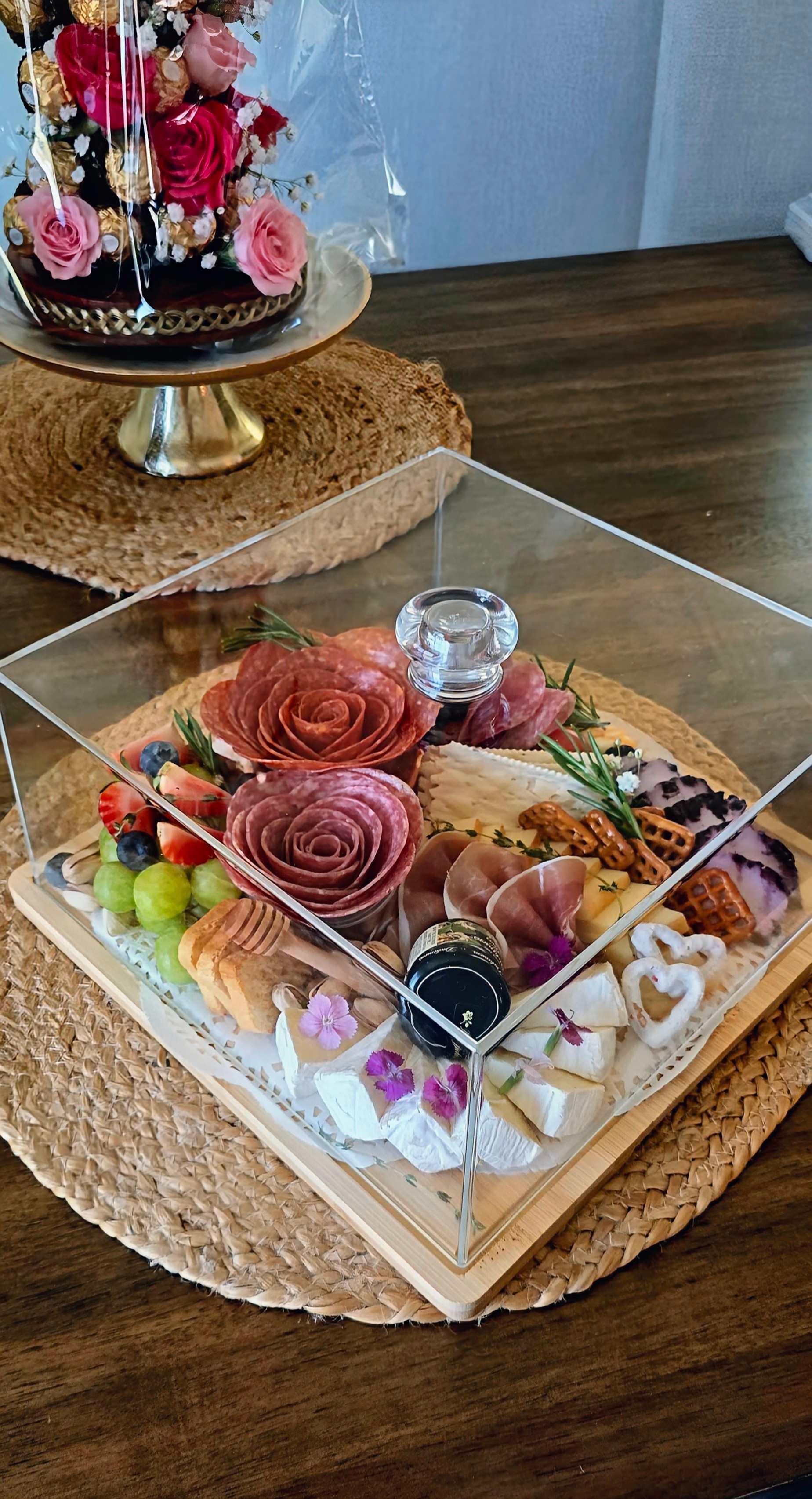 Assorted desserts and fruits arranged in a clear display case on a wooden table.