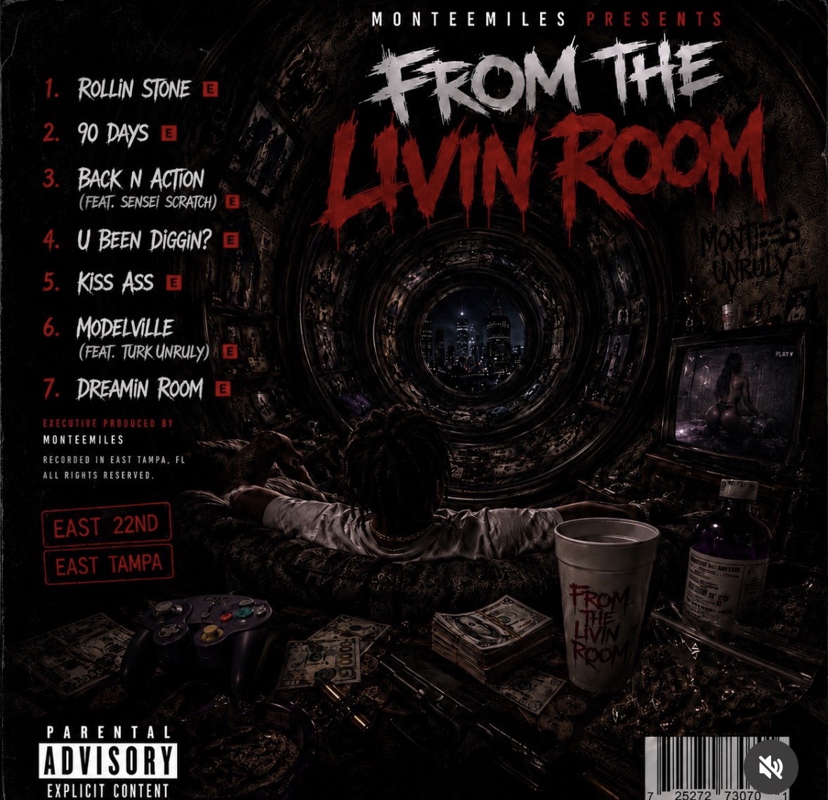 Dark room with a person at a desk, computer screens, and a cup with text, music tracklist on the wall, and parental advisory label.