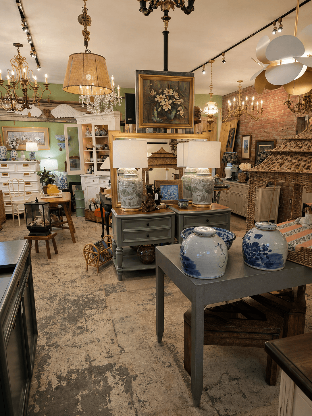 Interior of an antique shop with furniture, lamps, paintings, and decorative items arranged in a cozy space.