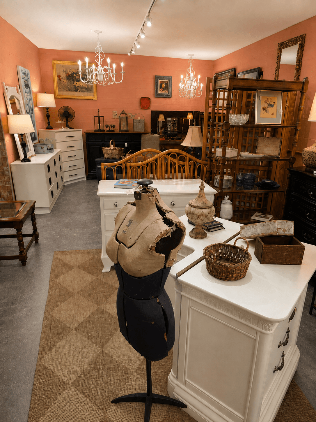 Room with peach walls, white furniture, chandelier, and various decorative items including vases and framed art, with a mannequin in the foreground.