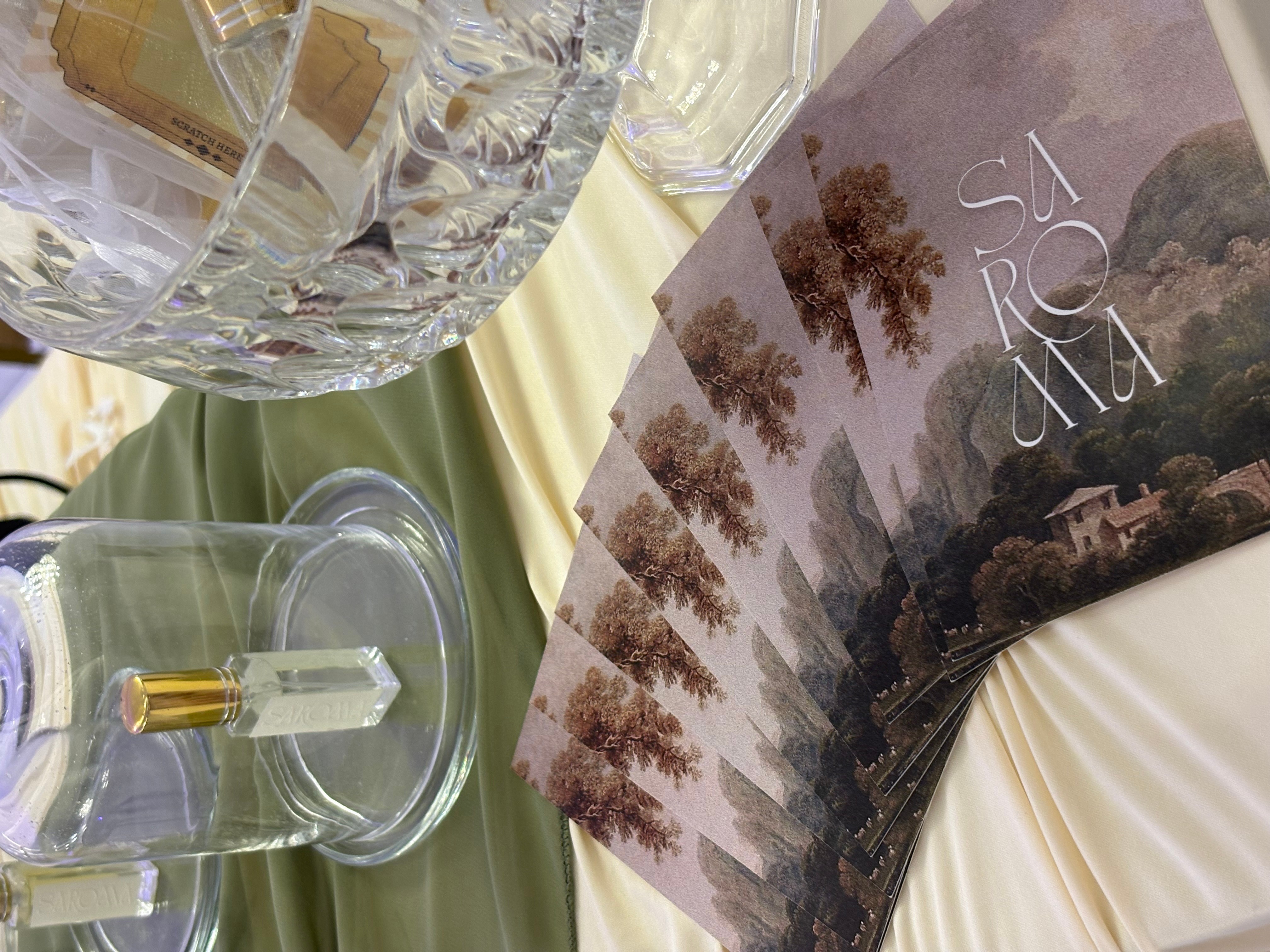 Table setting with glassware and a brochure, with a soft-colored tablecloth and a landscape image on the brochure.