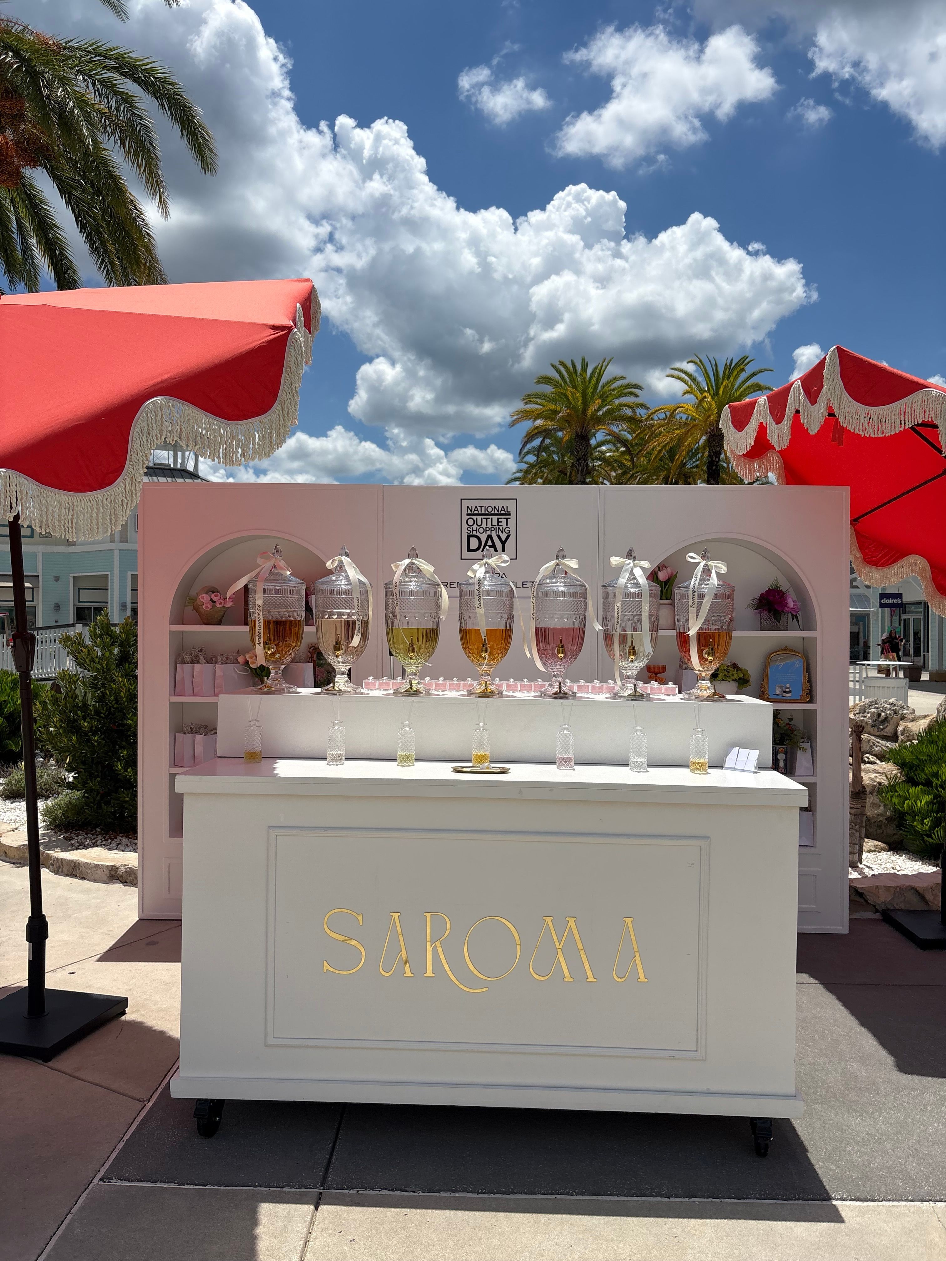 Outdoor display of skincare products on a white stand with a blue sky and clouds in background.