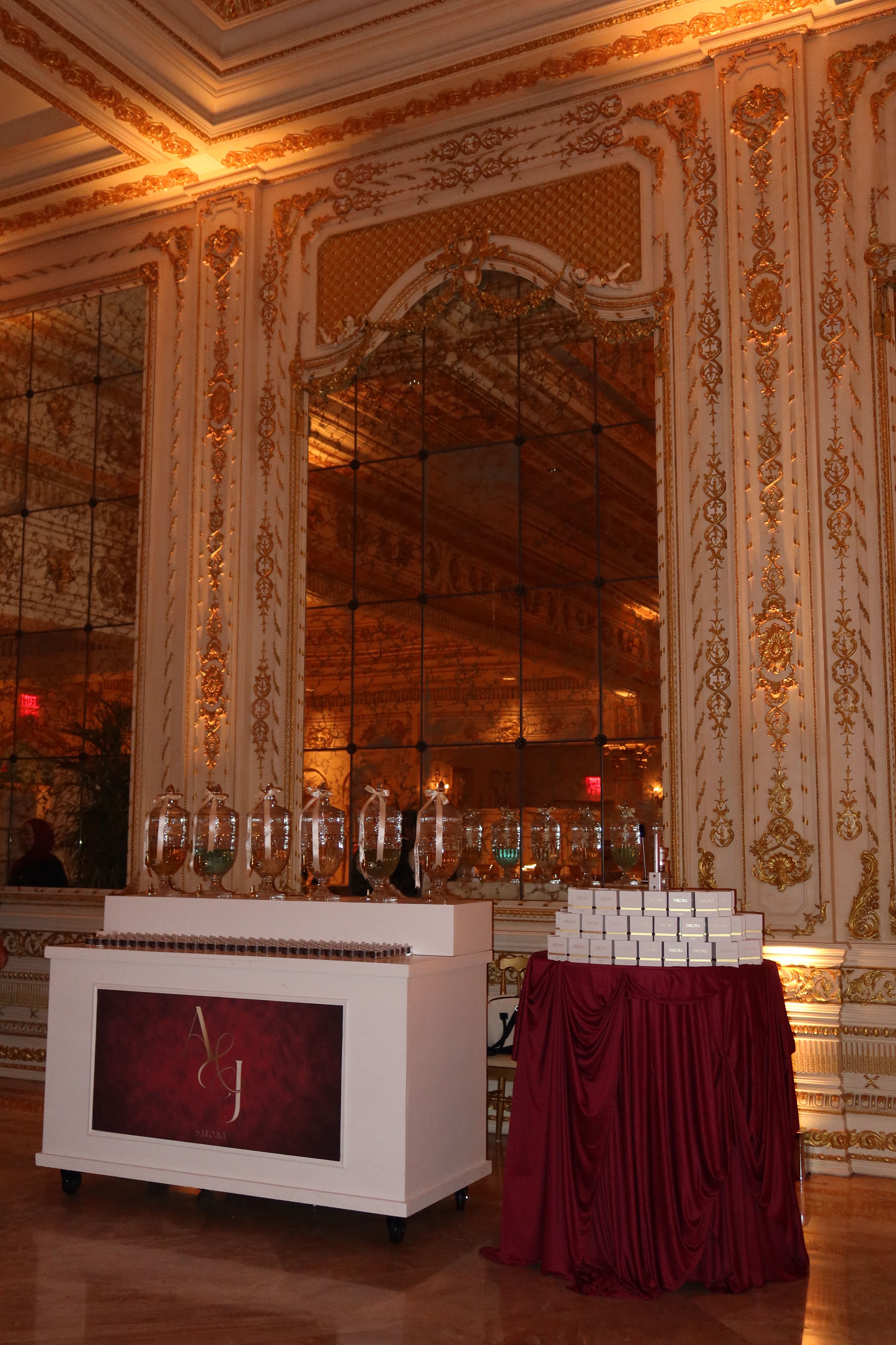 Elegant room with ornate gold and white decor, a mirror, and a bar with glasses and bottles, viewed sideways.