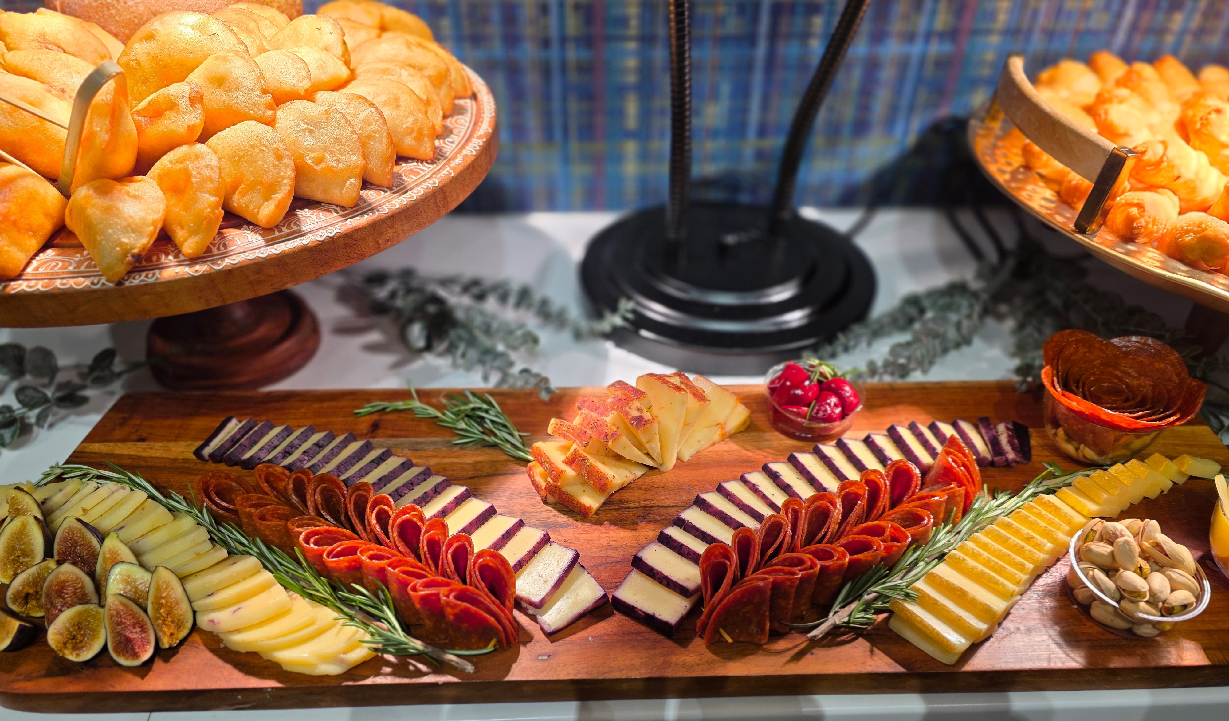 Assorted sliced cheeses, fruits, and snacks on a wooden board with decorative elements.