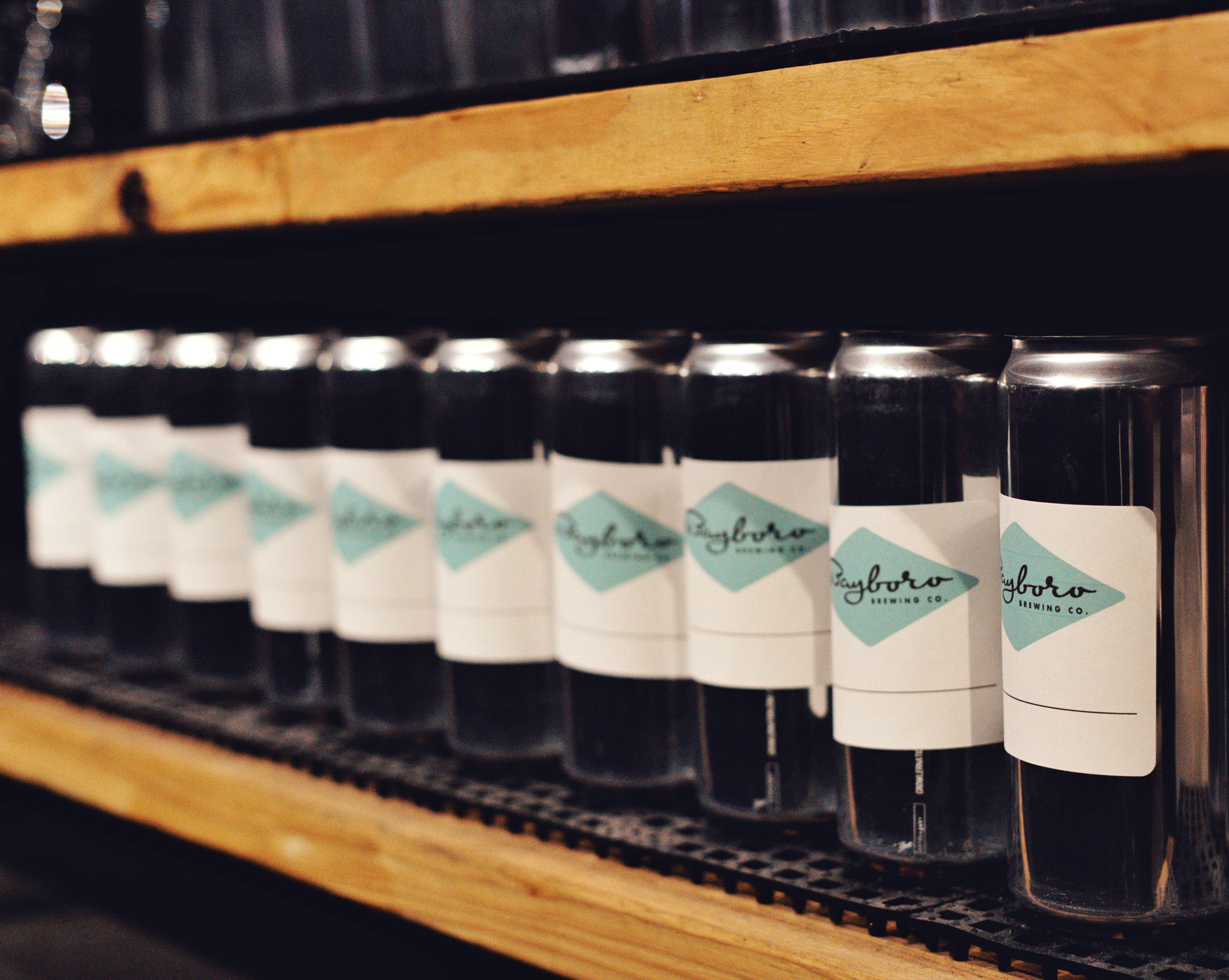 Rows of glass bottles on a wooden shelf with labels featuring a blue design.