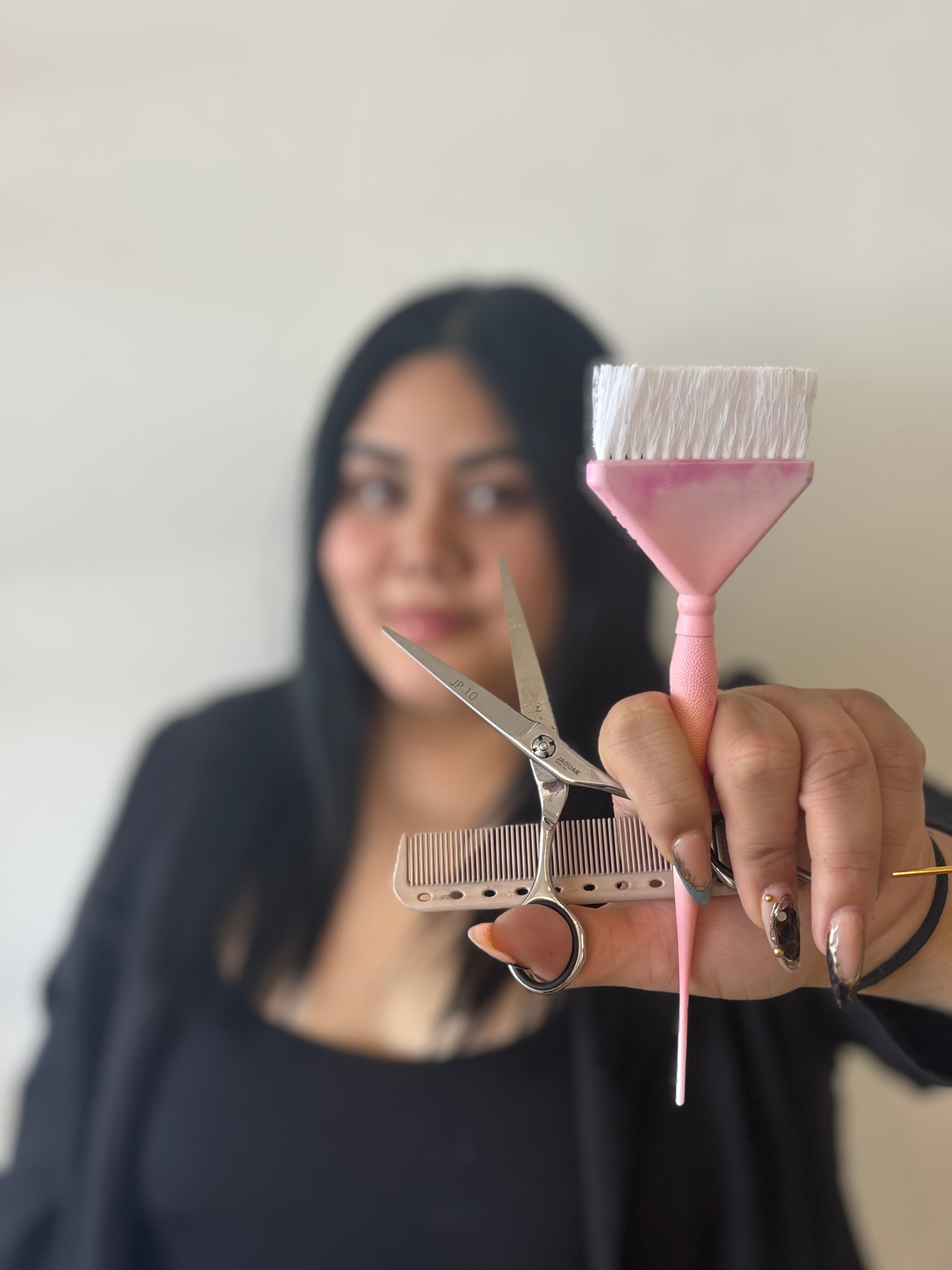 Woman holding a paintbrush with pink paint, smiling, blurred background, close-up of hand and brush.