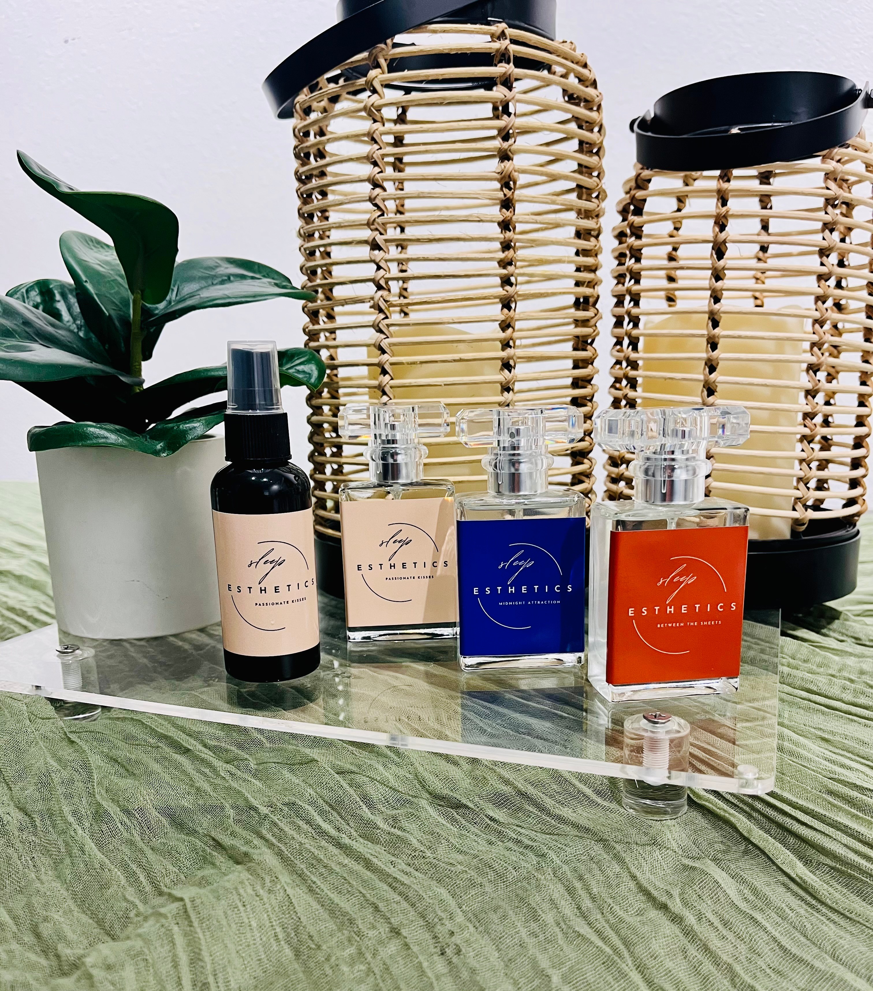 Assorted skincare products and glass cups on a clear tray, with woven baskets and a potted plant in the background.