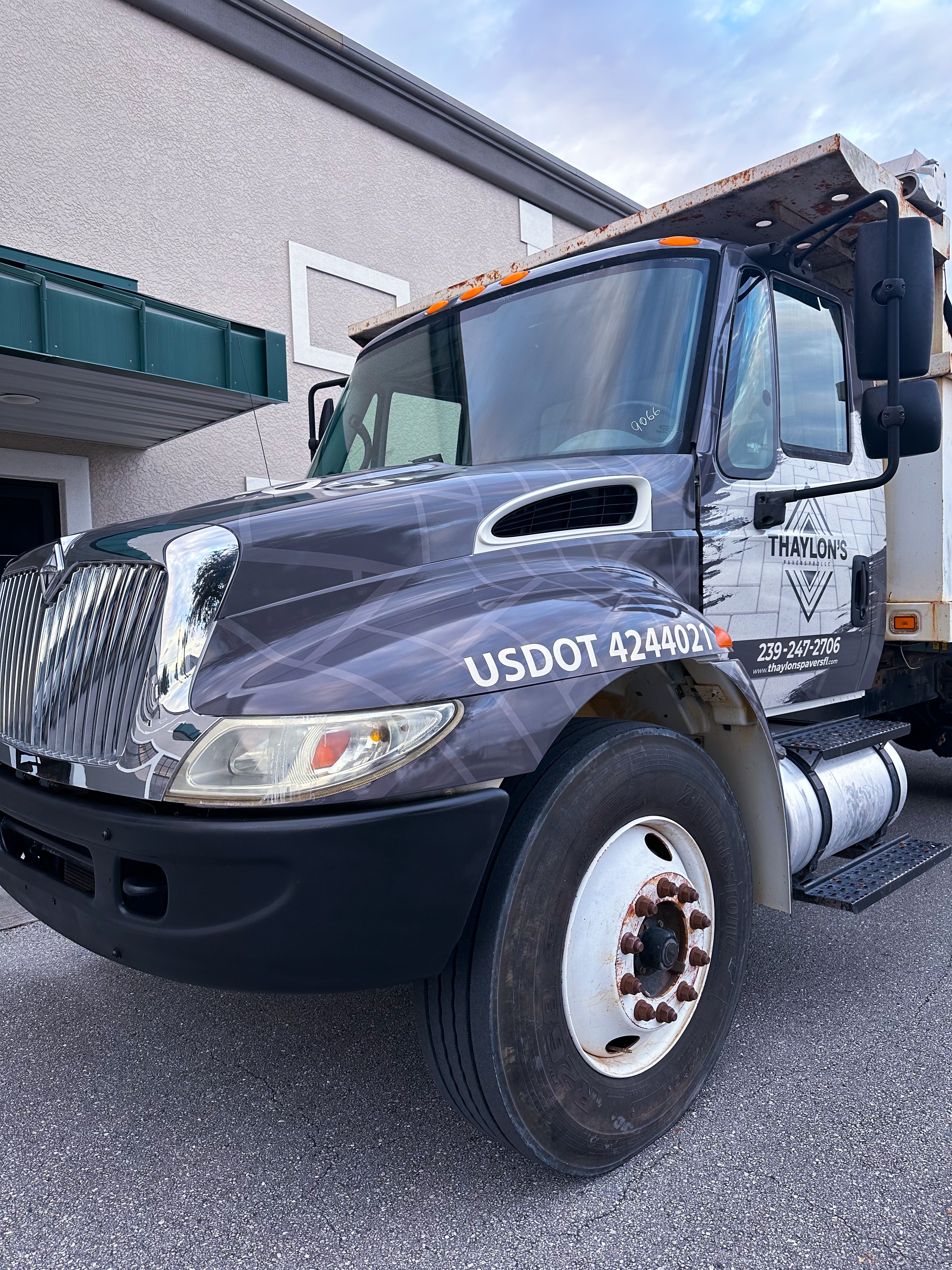 Front view of a large black and white truck parked outside a building, with a clear sky above.