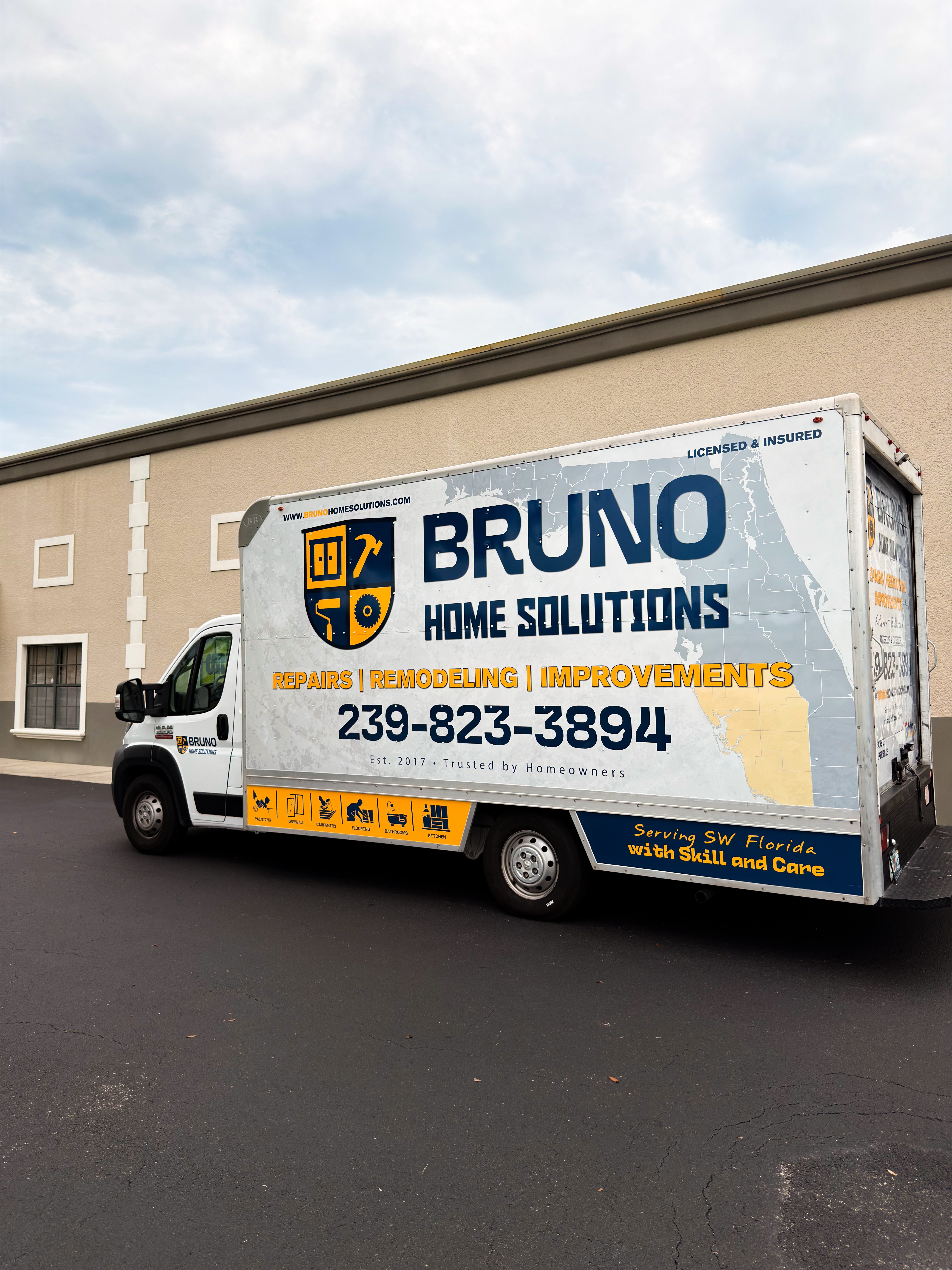 Delivery truck parked against a beige building with a cloudy sky above.