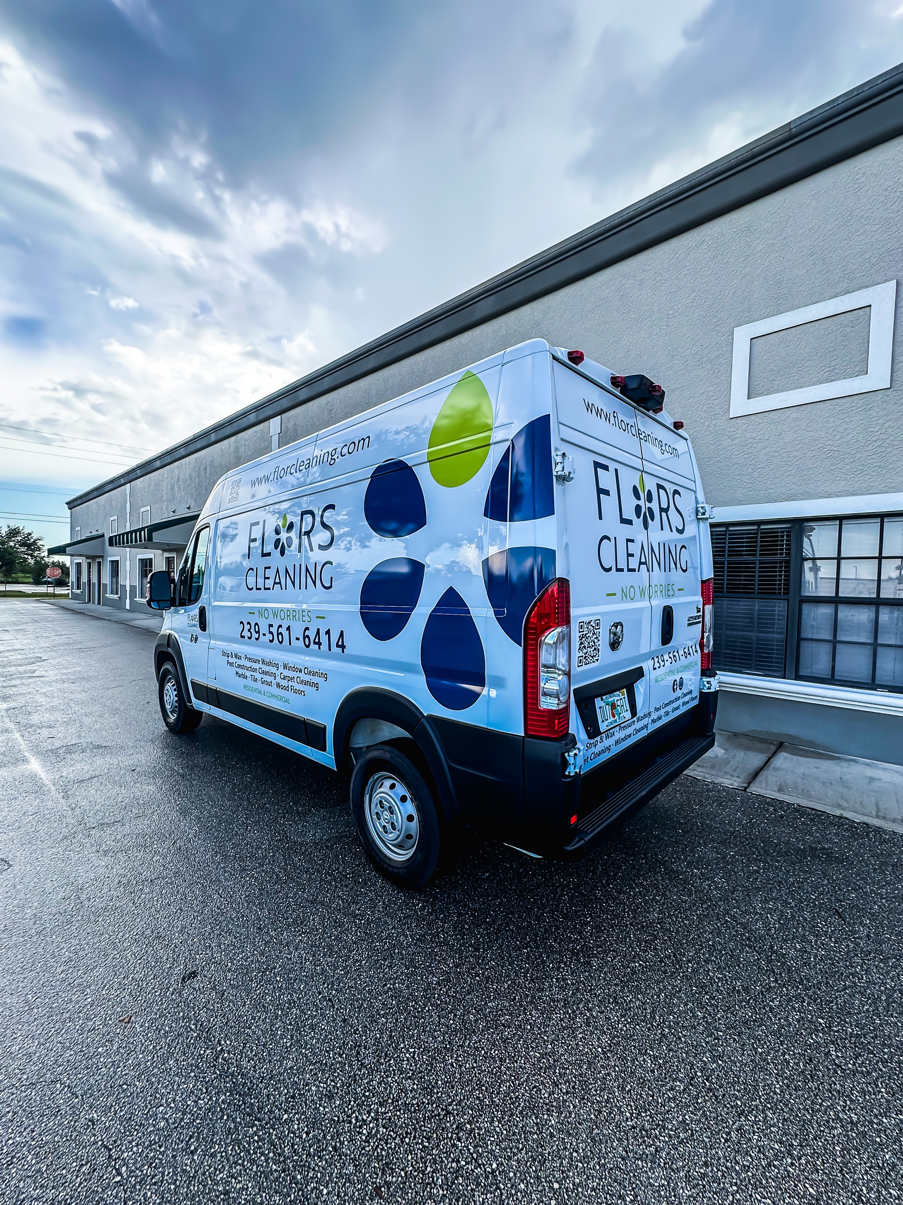 Cleaning van with colorful logo and text parked outside a building under a cloudy sky.