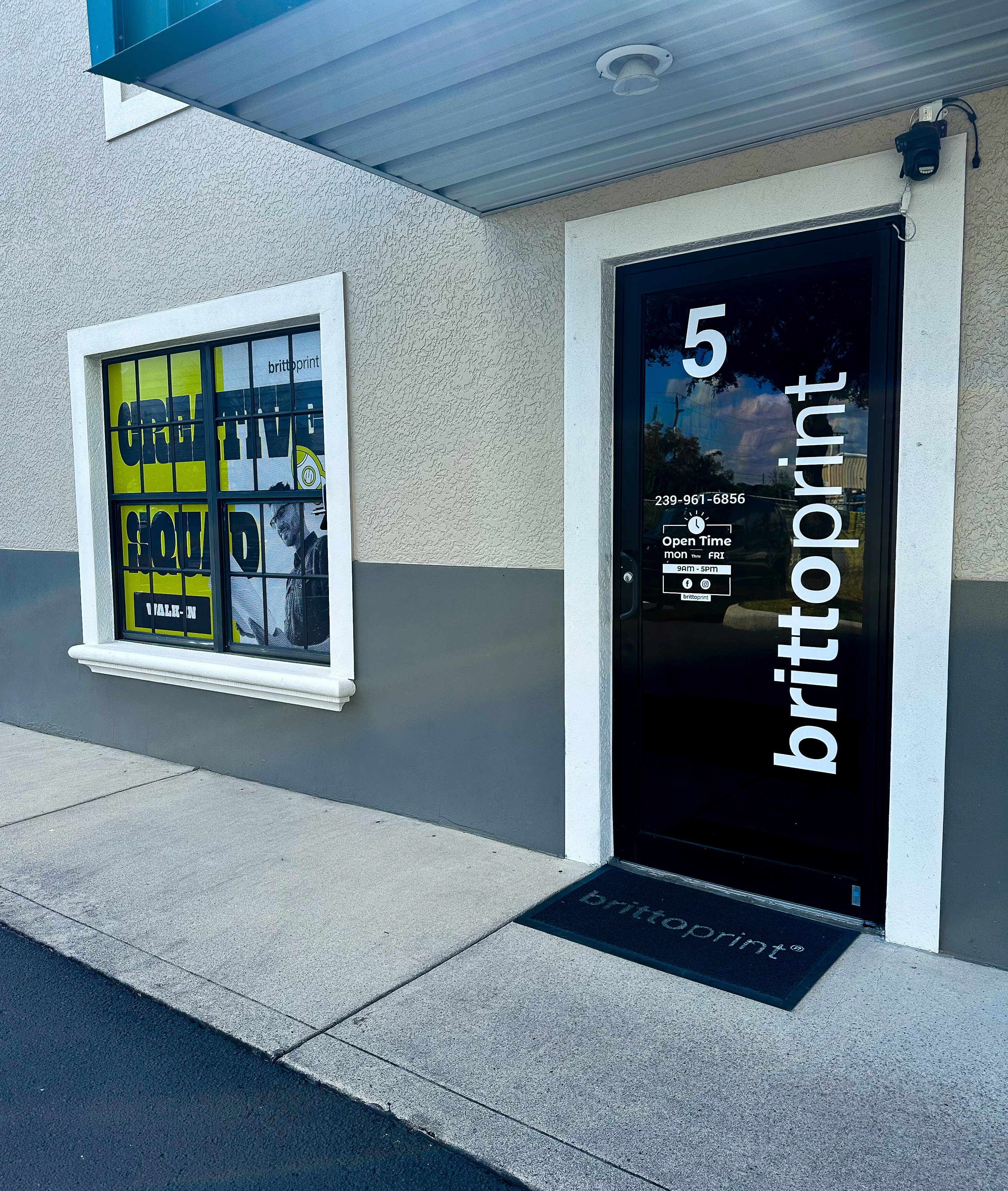 Storefront with a door labeled 'brittprint' and a window displaying colorful signs, building number 5 above the door.