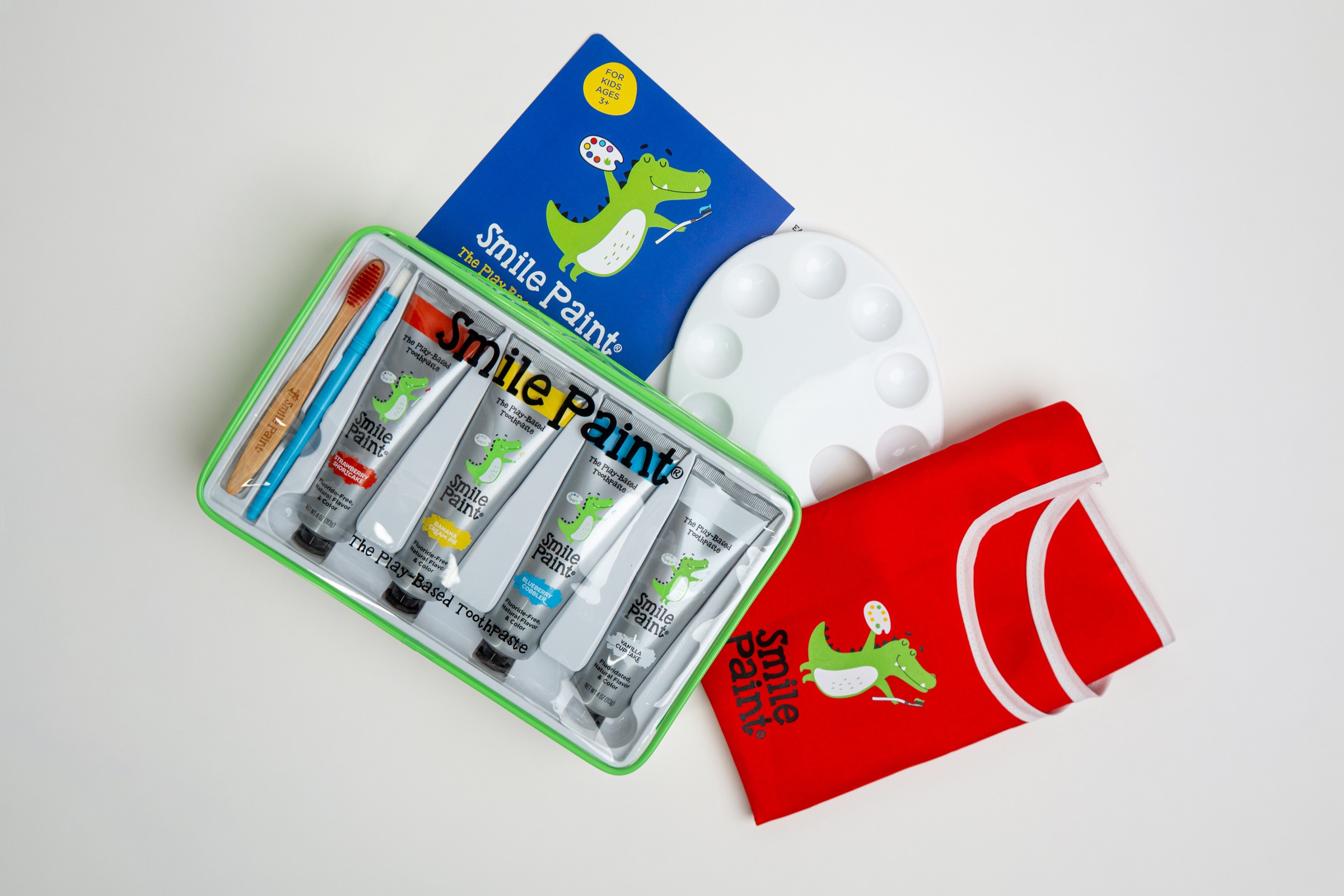 Set of paint supplies including a palette, red shirt, and a box of paint tubes with a crocodile logo.